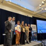 BETA Technologies team holding their Coolest Thing Made in Vermont award alongside Lieutenant Governor John Rodgers and Vermont Chamber President Amy Spear at the Vermont Manufacturing Summit.