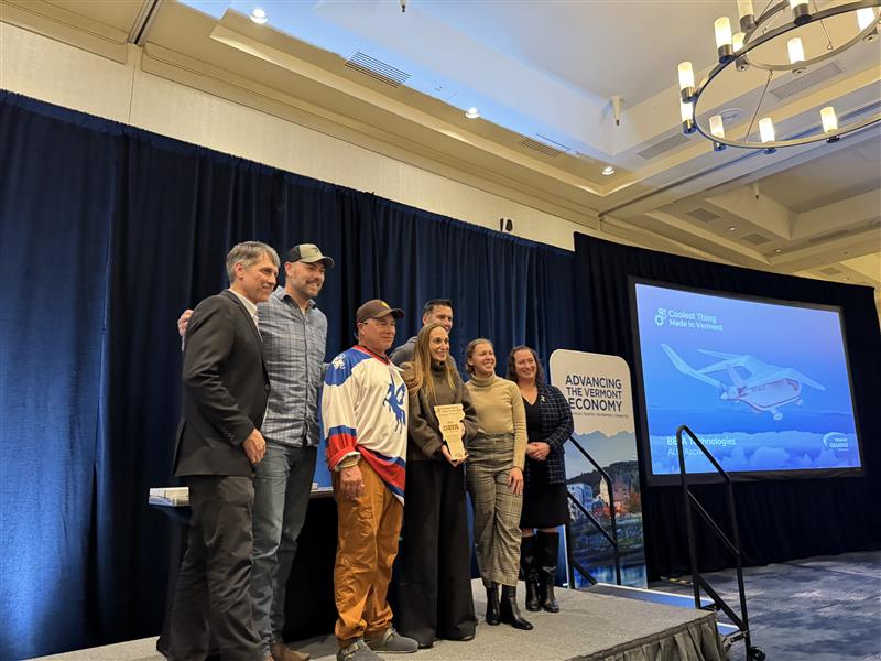 BETA Technologies team holding their Coolest Thing Made in Vermont award alongside Lieutenant Governor John Rodgers and Vermont Chamber President Amy Spear at the Vermont Manufacturing Summit.